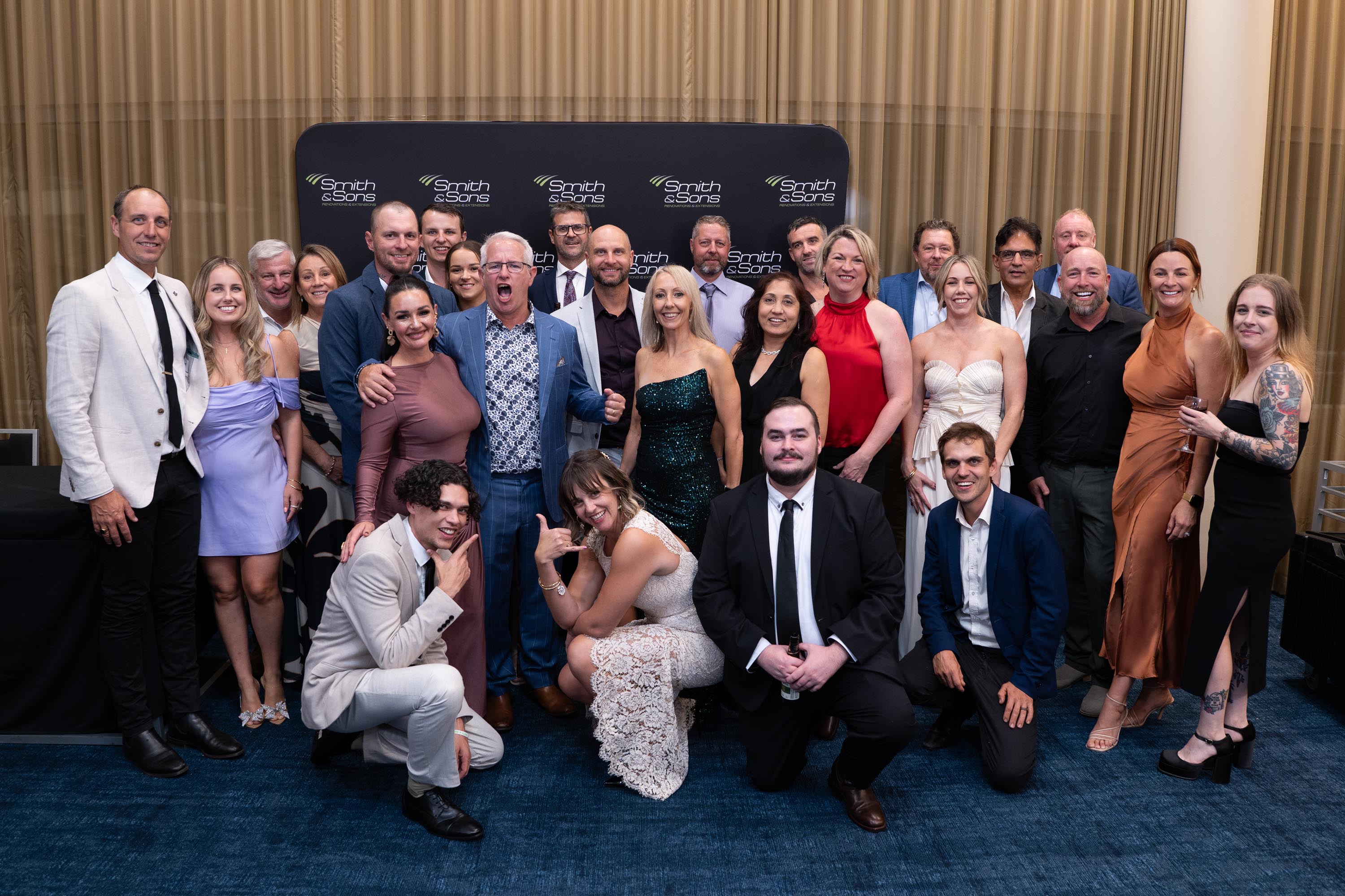 Full conference group photographed in formal wear at the Smith & Sons backdrop