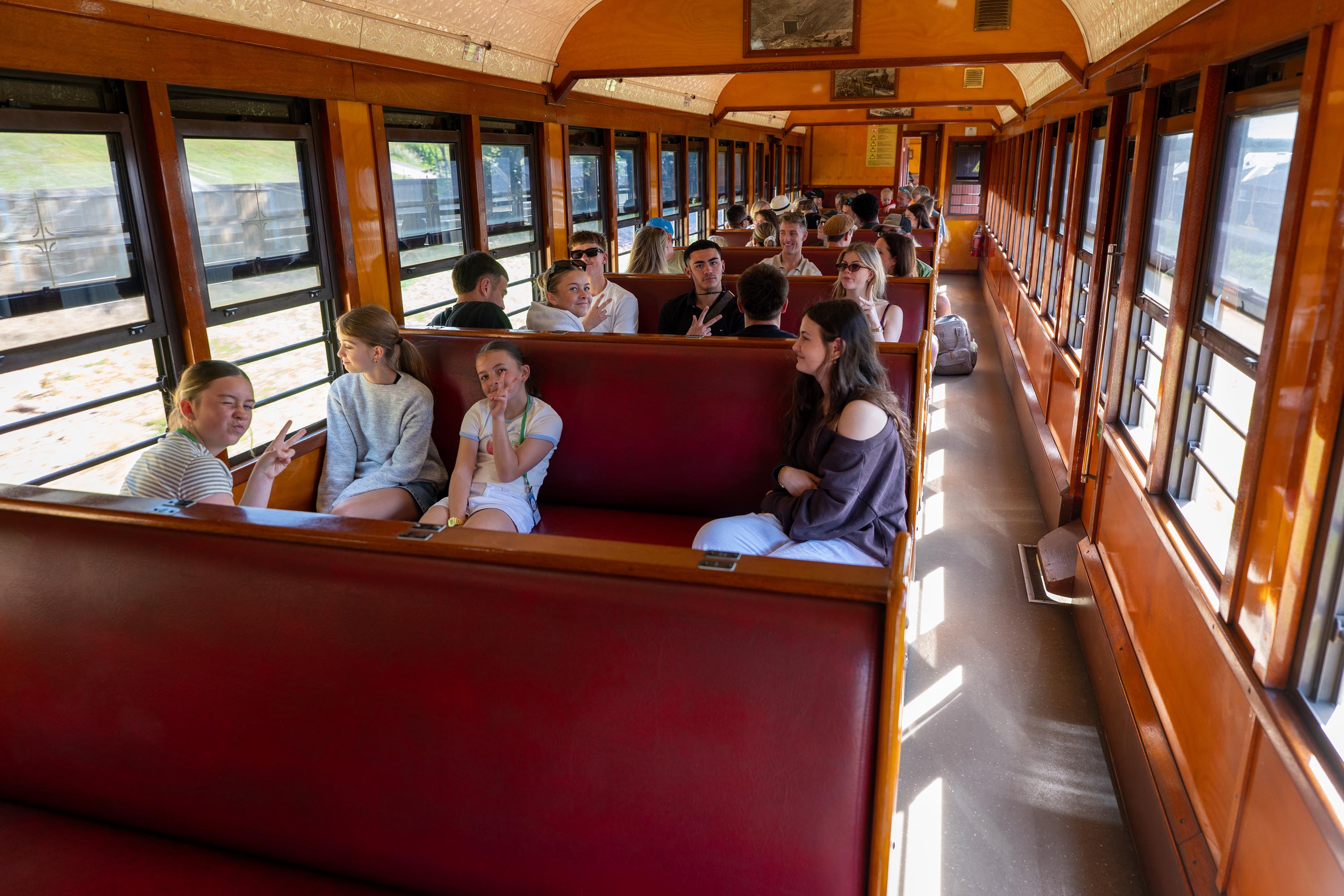 Young guests seated in the red leather booths of a heritage train carriage